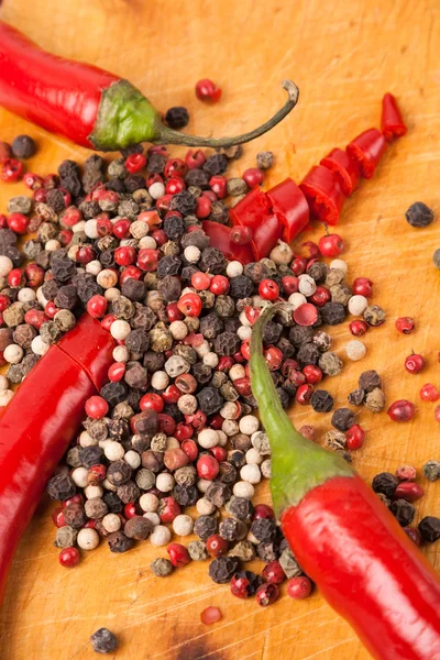 Cut capsicum chili pepper and peppercorn on wooden board Stock Photo