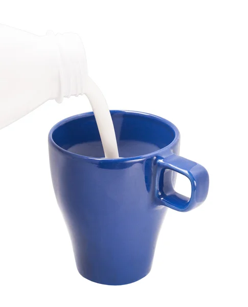 Pouring milk from bottle in blue cup — Stock Photo, Image