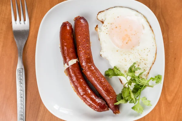 Embutidos y huevo frito en plato blanco en la mesa —  Fotos de Stock