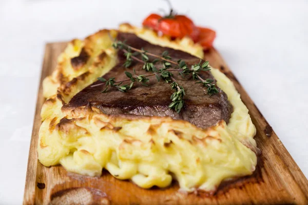 Vlees steak met aardappel puree gesteund op een houten bord — Stockfoto