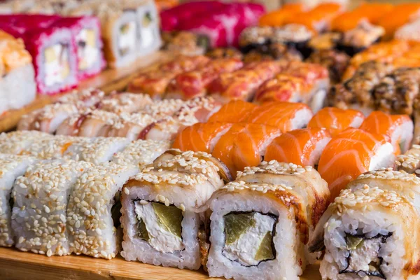 Sushis assortis et rouleaux sur panneau de bois dans la lumière sombre — Photo