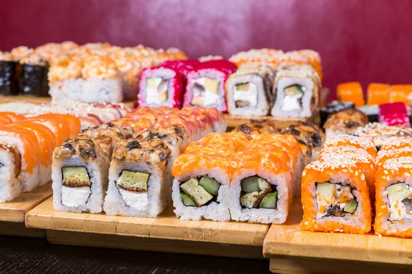 Geassorteerde sushi en rollen op een houten bord in donkere licht — Stockfoto