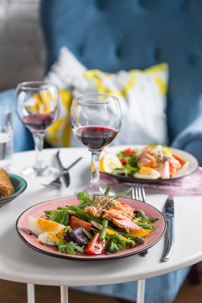 Salad with salmon and verdure in plate on table with blue chair — Stock Photo, Image