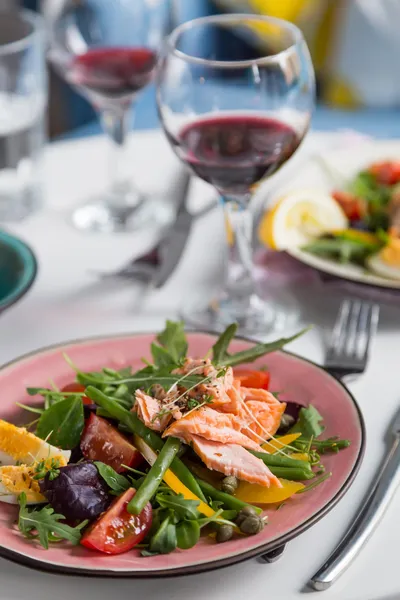 Salad with salmon and verdure in plate on table with blue chair — Stock Photo, Image