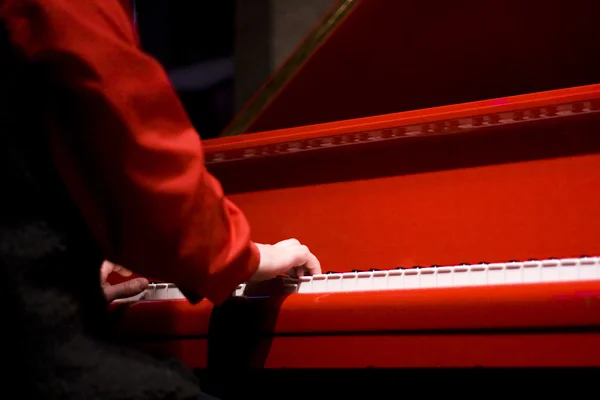 Handen van de pianist op de rode piano — Stockfoto