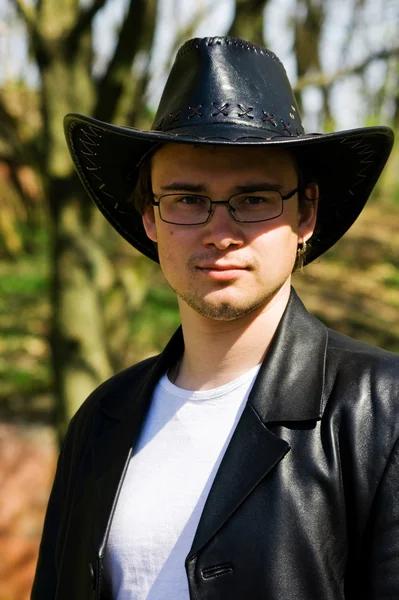 Jeune homme attrayant dans un manteau et un chapeau en cuir noir — Photo