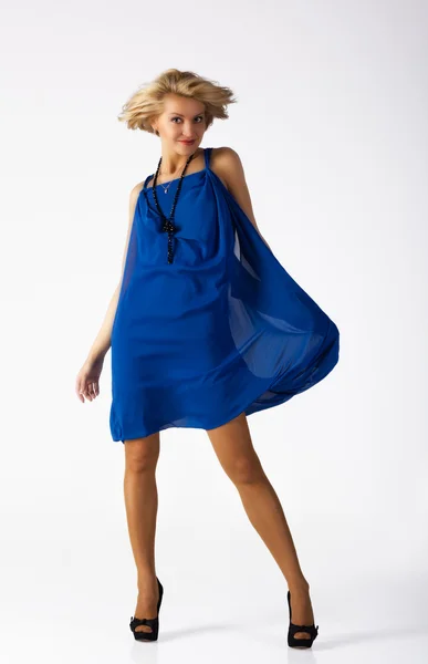 Attraktiv ung kvinna i en blå klänning som står i studion — Stockfoto