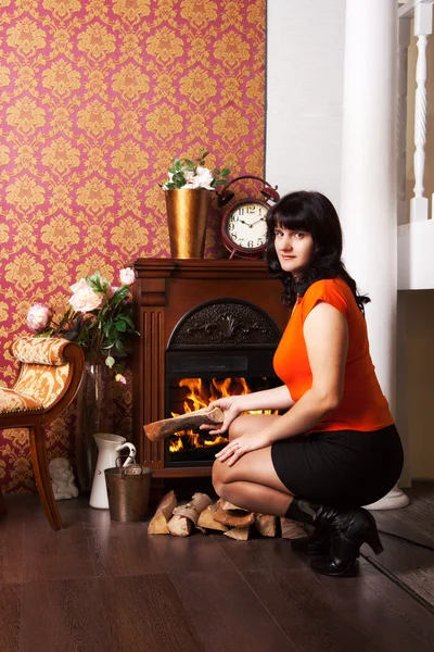 Young beautiful woman sits near the fireplace — Stock Photo, Image