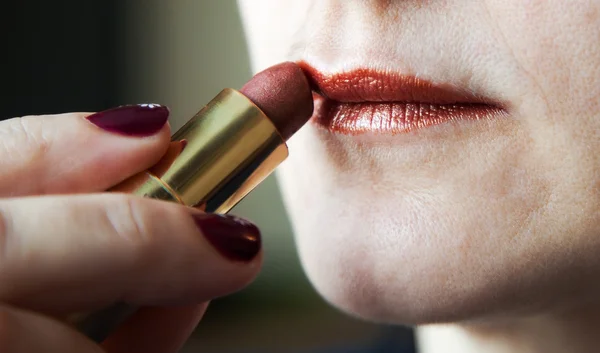 Vrouw schildert lippen met lippenstift — Stockfoto