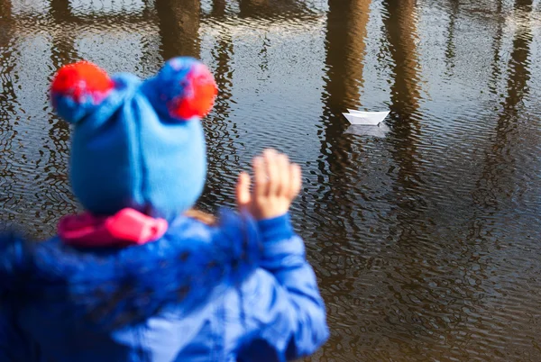 Tjej viftar ett papper båt flyter i bäcken — Stockfoto