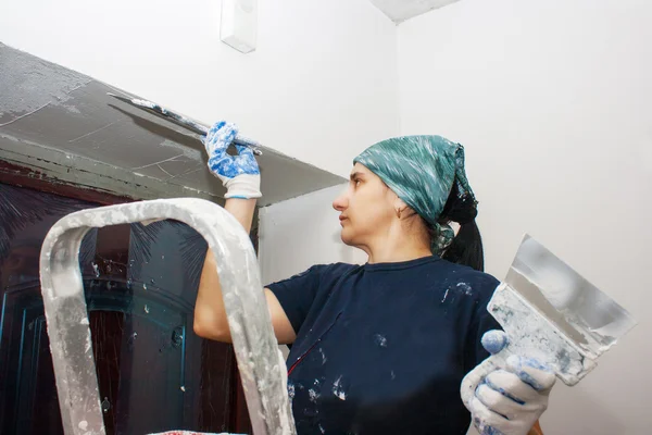 Mujer joven obtiene pared de yeso blanco —  Fotos de Stock