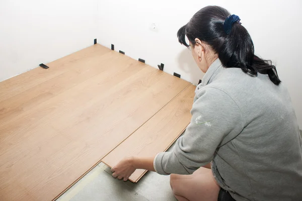 Jeune femme met stratifié plancher — Photo