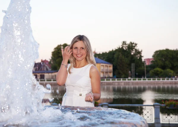 Jovem bela mulher em um vestido branco perto da fonte — Fotografia de Stock