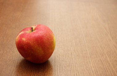 Masanın üzerinde duran büyük parlak kırmızı elma. Kapalı mekanda yakın çekim