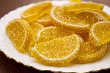 Marmelat limon dilimleri beyaz bir tabakta, ahşap bir masada yakın plan çekimde.