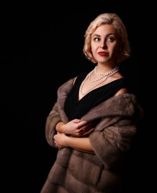 Stüdyoda siyah arka planda kürklü sarışın bir kadının portresi.