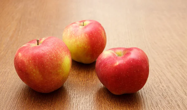 テーブルの上に3つの大きな赤いリンゴが木製のテーブルの上に横たわっています 屋内クローズアップ — ストック写真