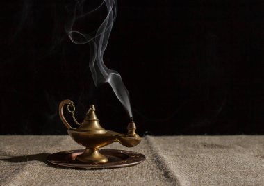 Aladdin 'in sihirli lambası masada sigara içiyor. Siyah arkaplanda kapalı çekim