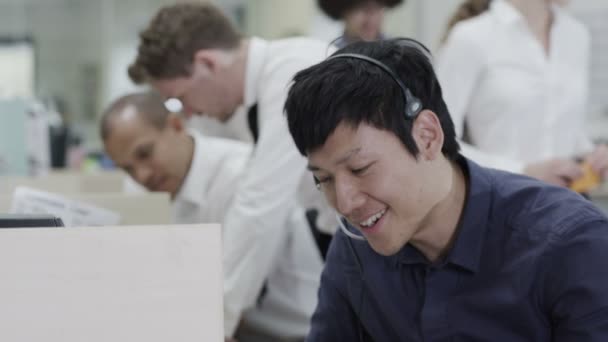 Cheerful young customer service operator, at work in a busy call center — Stock Video