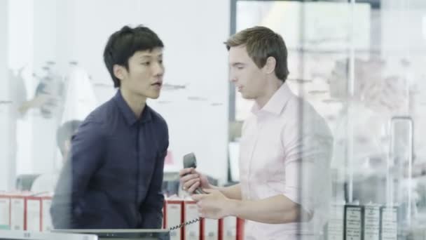 Vardagligen klädda unga professionella man på telefonen i ett modernt kontor — Stockvideo