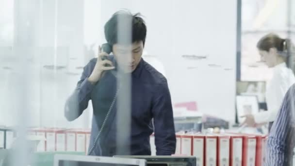 Vardagligen klädda unga professionella man på telefonen i ett modernt kontor — Stockvideo