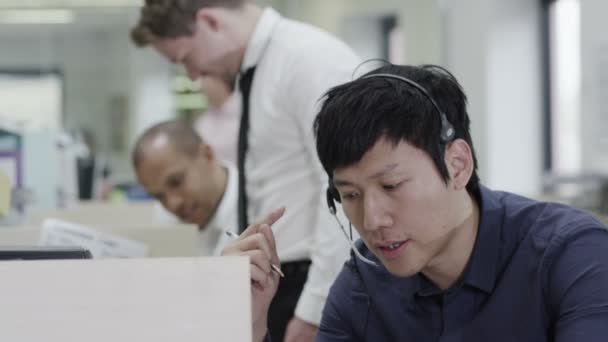 Alegre joven operador de servicio al cliente, en el trabajo en un centro de llamadas ocupado — Vídeos de Stock