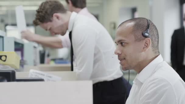 Alegre joven operador de servicio al cliente en el trabajo en un centro de llamadas ocupado — Vídeos de Stock