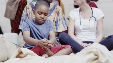 charity organisation gelen tıbbi çalışan genç bir çocuk annesi ile sohbet eder.