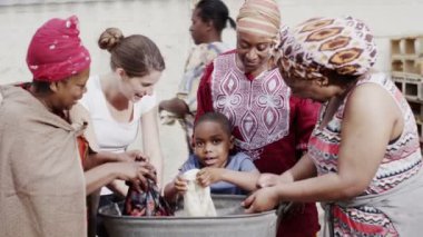 African aile ve toplum üyeleri birlikte, çamaşır giyim el ile çalışma