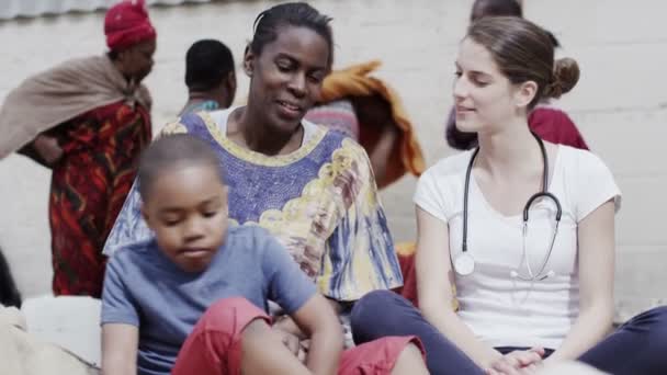 Medical worker from charity organisation chats with the mother of a young boy — Stock Video