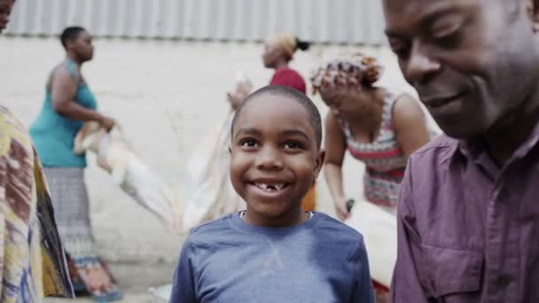 彼の家族やコミュニティのメンバーと満足の笑みを浮かべてアフリカ少年のポートレート — ストック動画