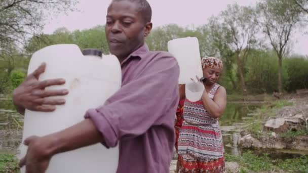 Aldeanos africanos en el río llenan contenedores con tanta agua como pueden llevar — Vídeos de Stock