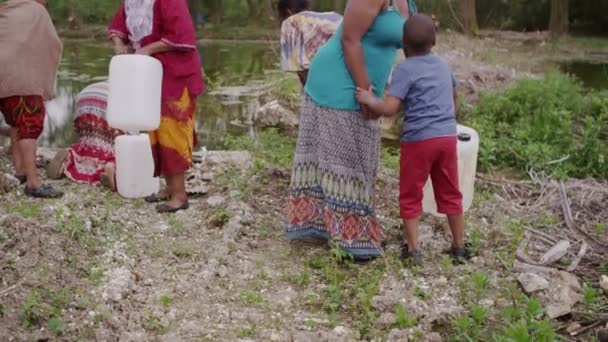 Αφρικανική χωρικοί στον ποταμό συμπληρώστε τα δοχεία με όσο νερό μπορούν να συνεχίσουν — Αρχείο Βίντεο