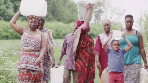 Afrikaanse dorpelingen reizen samen uitvoering containers gevuld met water — Stockvideo