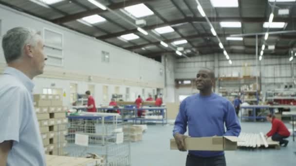 Fröhlicher Fabrik- oder Lagerarbeiter, der sich vom Vorarbeiter instruieren lässt — Stockvideo