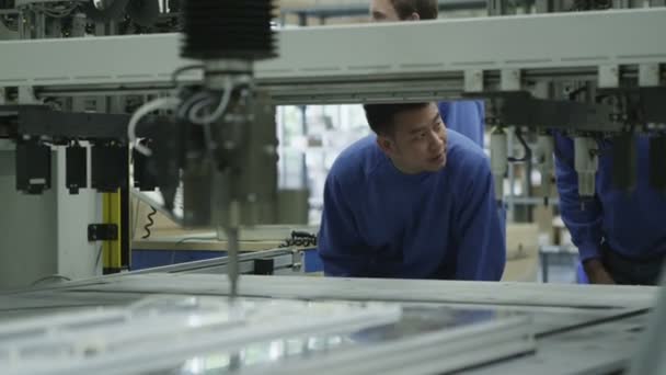 Male machine operators in a factory checking the process — Stock Video