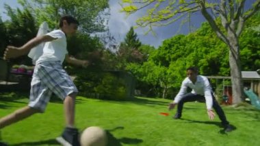 schattige jonge jongen sporten met zijn vader, in de tuin op een zomerdag