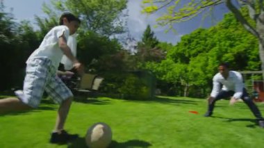 schattige jonge jongen sporten met zijn vader, in de tuin op een zomerdag