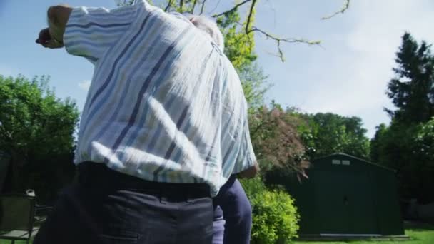 Romántica pareja jubilada abrazar y mirar hacia fuera sobre su jardín en un día de verano — Vídeos de Stock