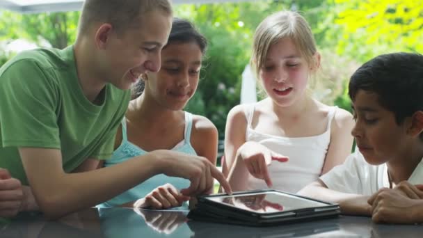 Young friends in the garden on a summer day playing with a computer tablet — Stock Video