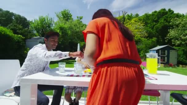 Aziatische en gelukkige familie eten lunch op het terras in de tuin — Stockvideo