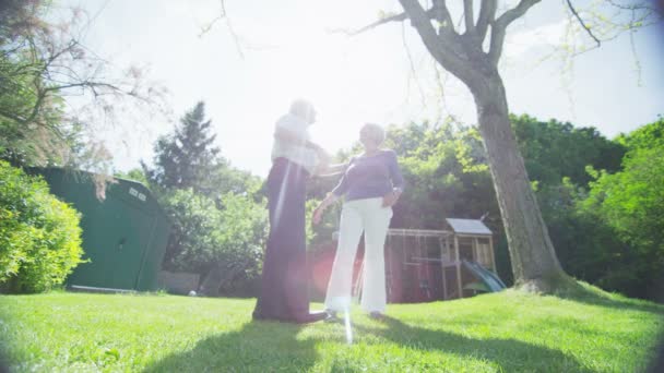 Casal aposentado romântico abraçar e olhar para fora sobre seu jardim em um dia de verão — Vídeo de Stock