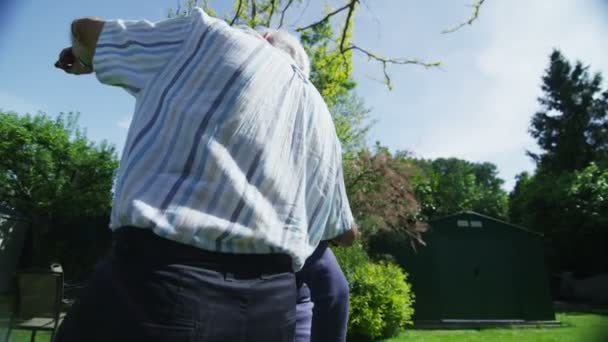 Romantic retired couple embrace and look out over their garden on a summer day — Stock Video