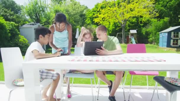 Young friends in the garden on a summer day playing with a computer tablet — Stock Video