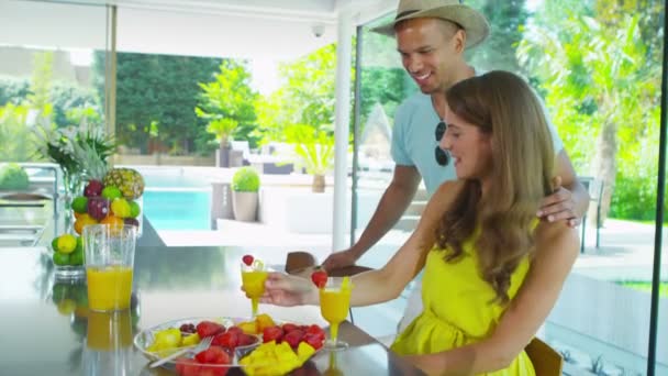 Feliz pareja joven bebiendo jugos saludables en la cocina del hogar moderno — Vídeos de Stock