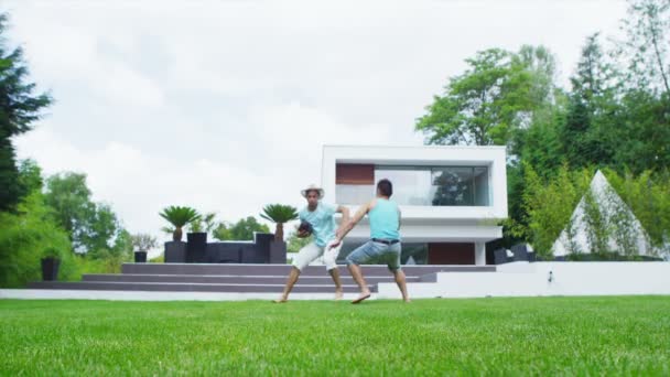 Атлетическая группа друзей-мужчин играет в футбол в саду современного дома — стоковое видео