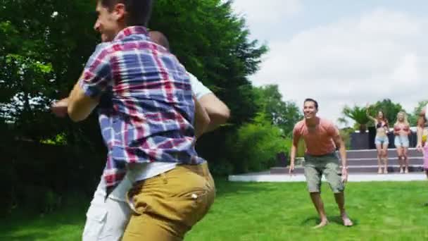 Athletic group of male friends play football in the garden of contemporary home — Stock Video