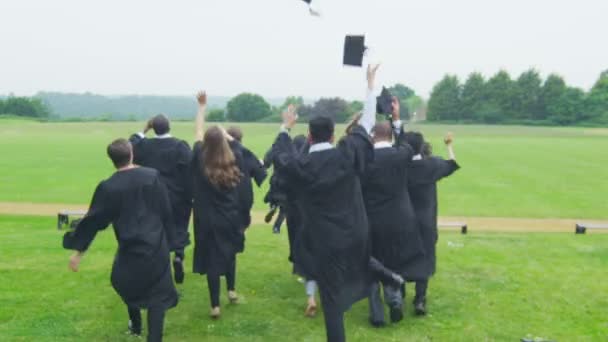 Gli studenti nel giorno della laurea corrono attraverso il paesaggio — Video Stock