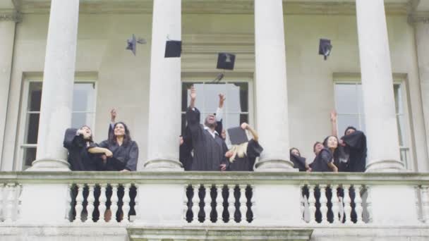 Estudiante amigos en día de graduación tirar gorras — Vídeo de stock