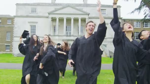 Los graduados corren y tiran sus gorras — Vídeo de stock